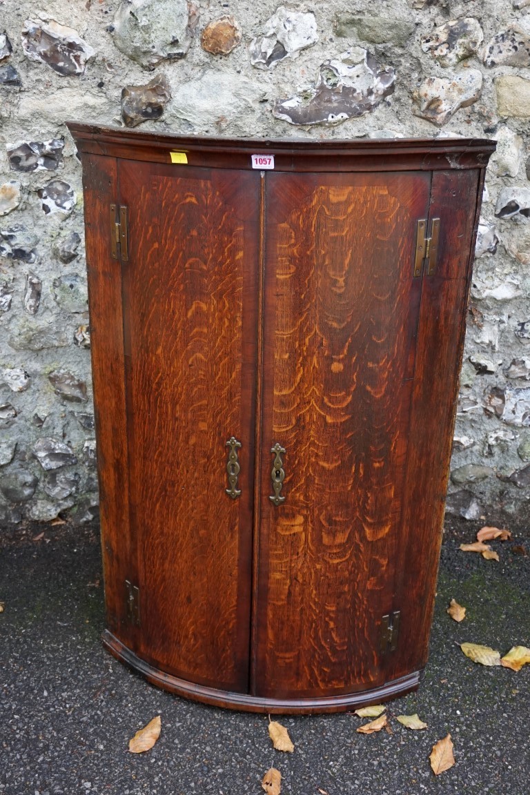 An oak and mahogany veneered bow front hanging corner cupboard, 104cm high x 68cm wide. This lot can