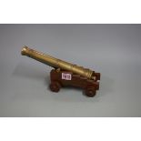 A cast brass model cannon, 26cm long, on wood four wheel stand.