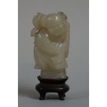A Chinese carved celadon jade boy, 5.5cm high, on fitted hardwood stand.