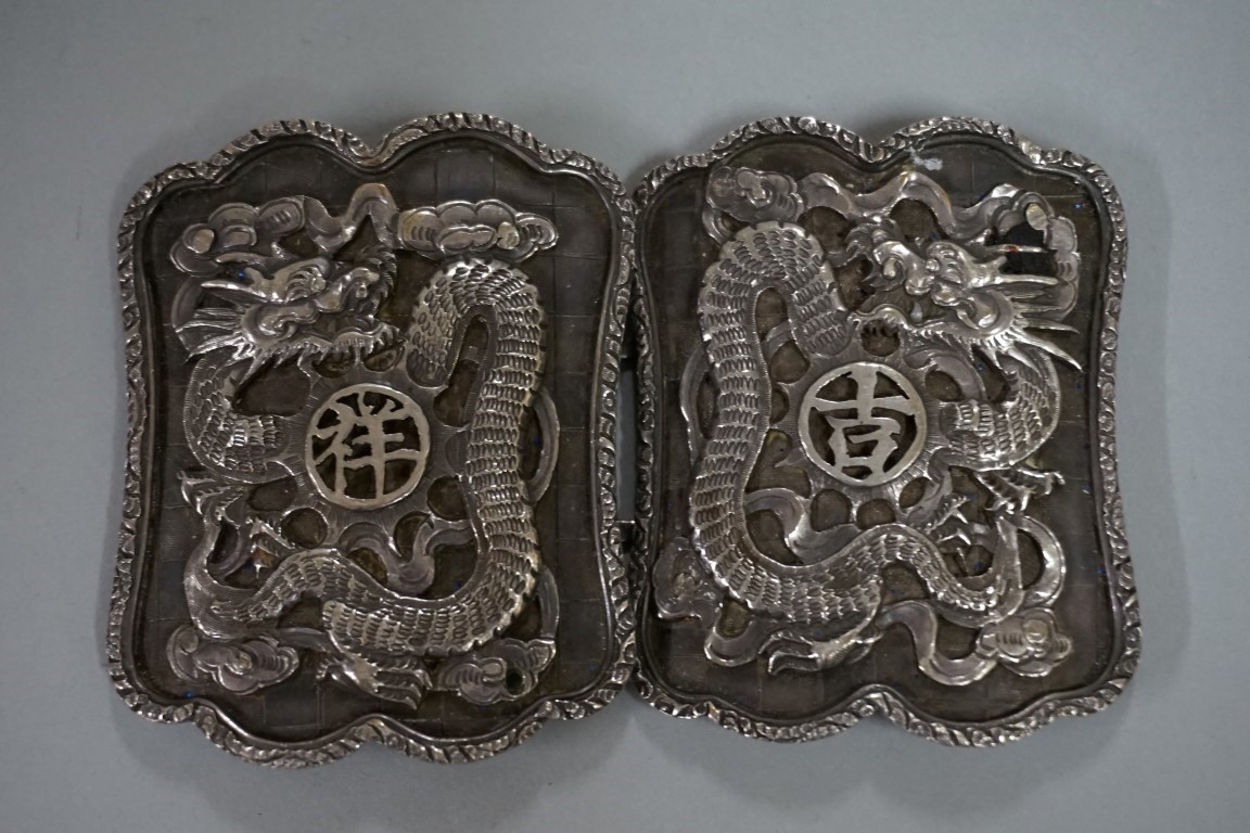 A Chinese silver belt buckle, by Kwan Wo, relief decorated with dragons, each half 6.5 x 5cm, 63g.