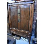 A late 19th/early 20th century Chinese hardwood side cabinet, the pair of panel doors opening to