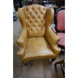 An 18th century style studded leatherette wing armchair.