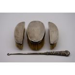 Three silver mounted brushes; together with a silver handled button hook.