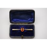 An orange garnet gold bar brooch, hallmarked 9ct, 5cm across, 1.9g gross weight, in fitted case.