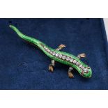 A diamond and green enamel salamander yellow metal brooch, having cabochon ruby eyes, 7.5cm long,
