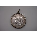 Coins: a US Liberty silver $1, mounted in an unmarked white metal pendant mount, 30.5g gross weight.