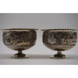 A pair of Indian white metal pedestal bowls, decorated village scenes, 8.5cm high.