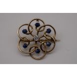 A diamond and sapphire yellow metal brooch/pendant, the central diamond approximately 0.25ct, 5.4g