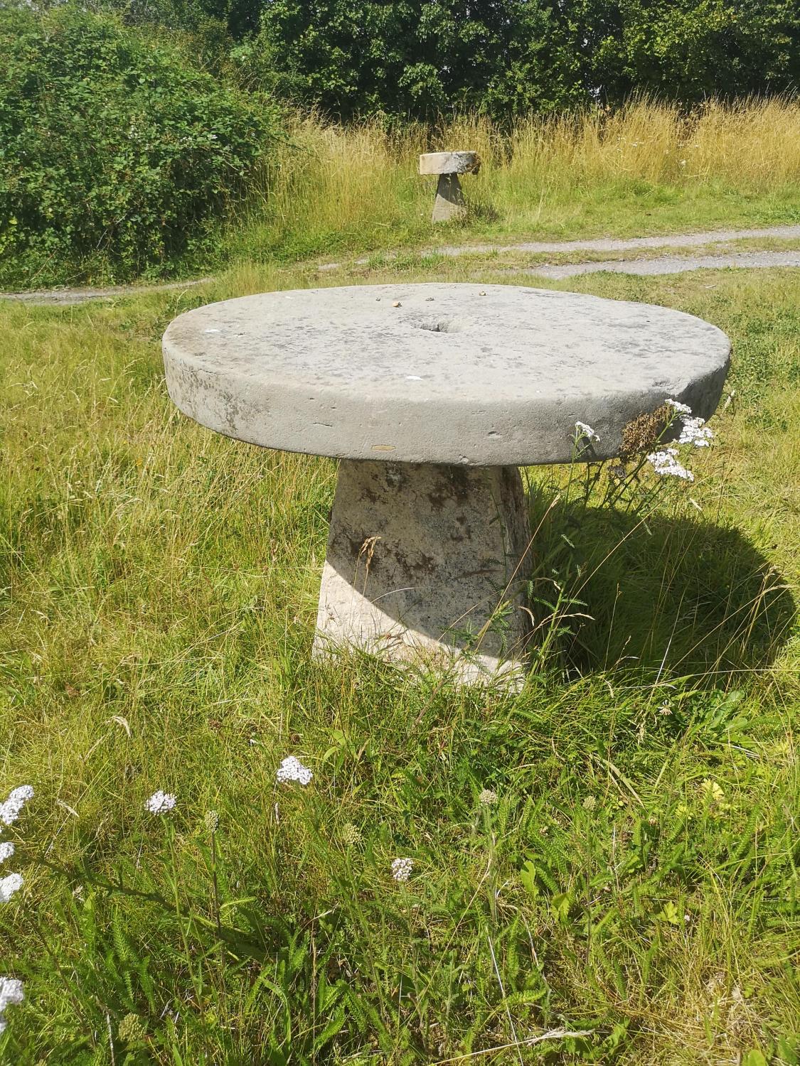 Garden Tables/Furniture: A carved stone table with millstone top on staddlestone base, 80cm high