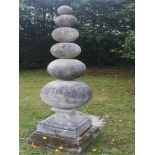 Sculpture: A composition stone obelisk, modern, comprising six graduated stone balls on square base,