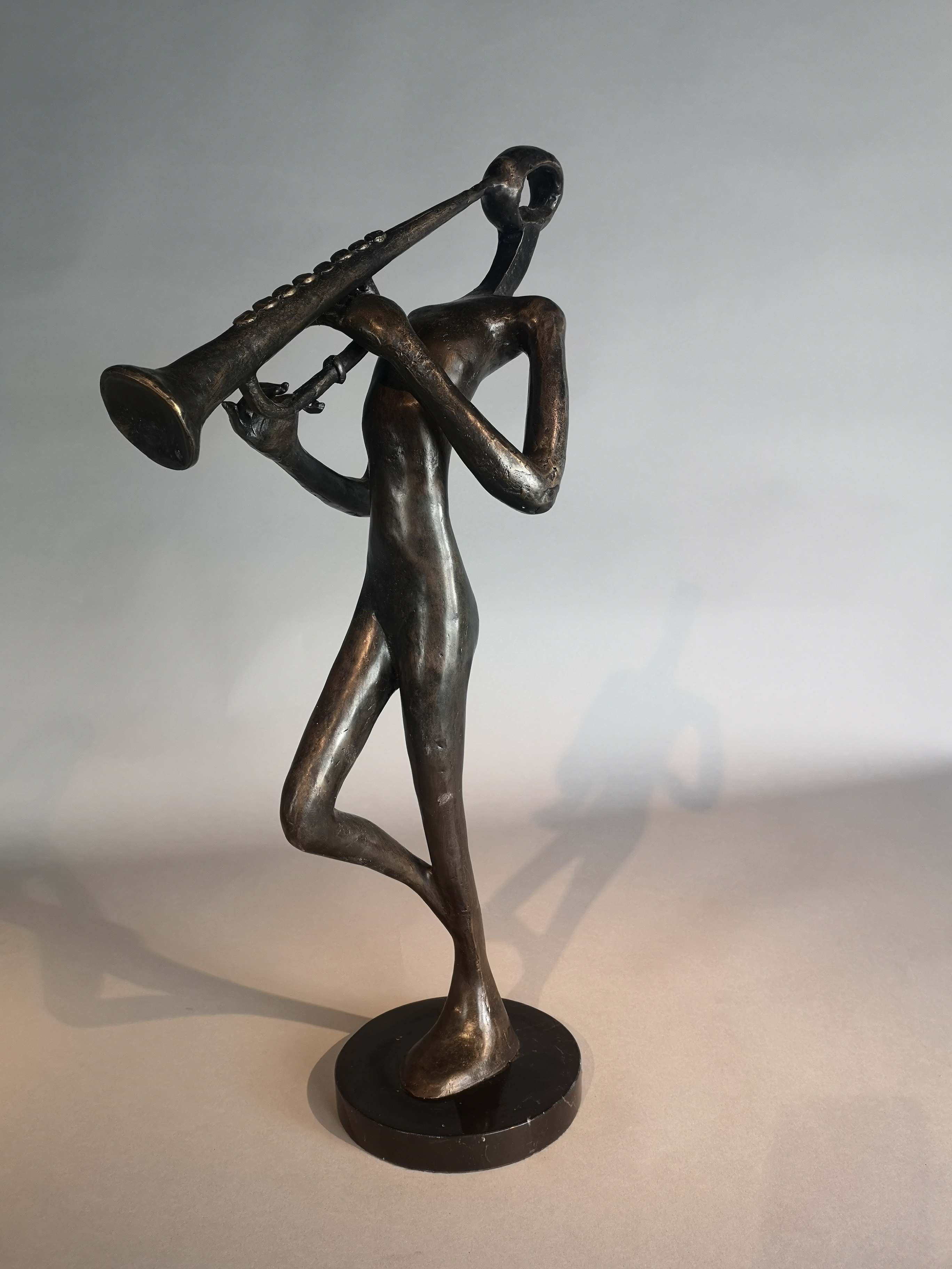 Sculpture: A bronze stylised figure playing a musical instrument modern on marble base 63cm high