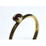 AN 18CT GOLD AND GARNET SOLITAIRE RING Having a single colet set stone (size P).