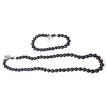 A BLACK PEARL NECKLACE AND MATCHING BRACELET The single row of pearls on a silver clasp. (necklace