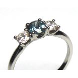 A PLATINUM, SAPPHIRE AND DIAMOND THREE STONE RING Having a round cut teal sapphire flanked by