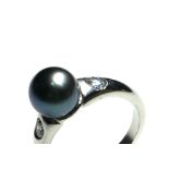 AN 18CT WHITE GOLD BLACK PEARL AND DIAMOND RING Having a single pearl flanked by round cut