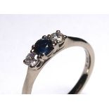 AN 18CT WHITE GOLD, SAPPHIRE AND DIAMOND THREE STONE RING Having a round cut sapphire flanked by