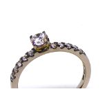 AN 18CT WHITE GOLD AND ROUND BRILLIANT CUT DIAMOND SOLITAIRE RING With diamond set shoulders,