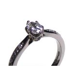 AN 18CT WHITE GOLD AND OVAL BRILLIANT CUT DIAMOND SOLITAIRE RING Flanked by diamond encrusted