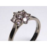 AN 18CT GOLD AND DIAMOND DAISY CLUSTER RING Having an arrangement of round cut diamonds (size L). (