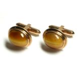 A VINTAGE PAIR OF 9CT GOLD AND TIGERS EYE GENT'S CUFFLINKS Having a cabochon cut stone in a plain
