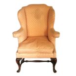 A 18TH CENTURY DESIGN WING ARMCHAIR With out-swept arms, raised on cabriole legs and pad feet joined