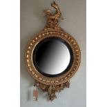 A REGENCY PERIOD GILTWOOD FRAMED CONVEX MIRROR Crested with a mythical beast above a circular