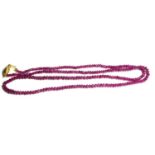 AN 18CT GOLD AND RUBY BEAD NECKLACE The single row of ruby beads with a scrolled gold clasp. (approx