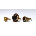 THREE VINTAGE 9CT GOLD AND GEM SET RINGS Comprising a gent's garnet set signet ring, a smoky topaz