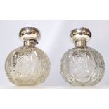 A LARGE PAIR OF EDWARDIAN SILVER AND CUT GLASS PERFUME BOTTLES Spherical form, having embossed
