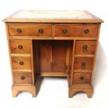 A GEORGIAN DESIGN YEW KNEEHOLE DESK With tooled leather top above an arrangement of eight drawers