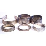 A COLLECTION OF SIX EARLY 20TH CENTURY SILVER BANGLES Three with engraved decoration and two with