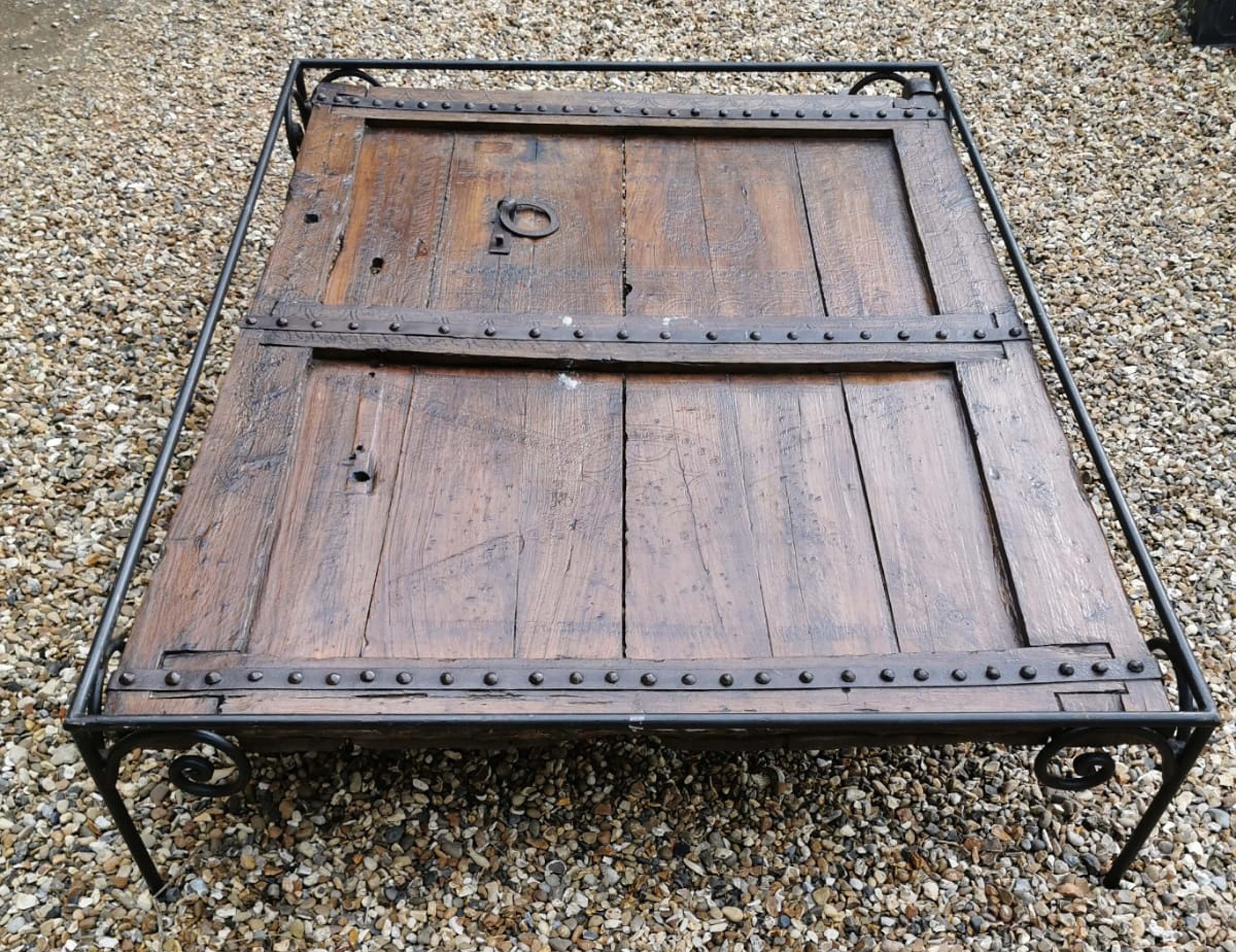 A LARGE 18TH/19TH CENTURY HARDWOOD DOOR With lightly carved decoration and heavy iron strap work,