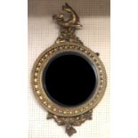 A REGENCY PERIOD GILT FRAMED CONVEX MIRROR Crested with a mythical beast above a circular plate