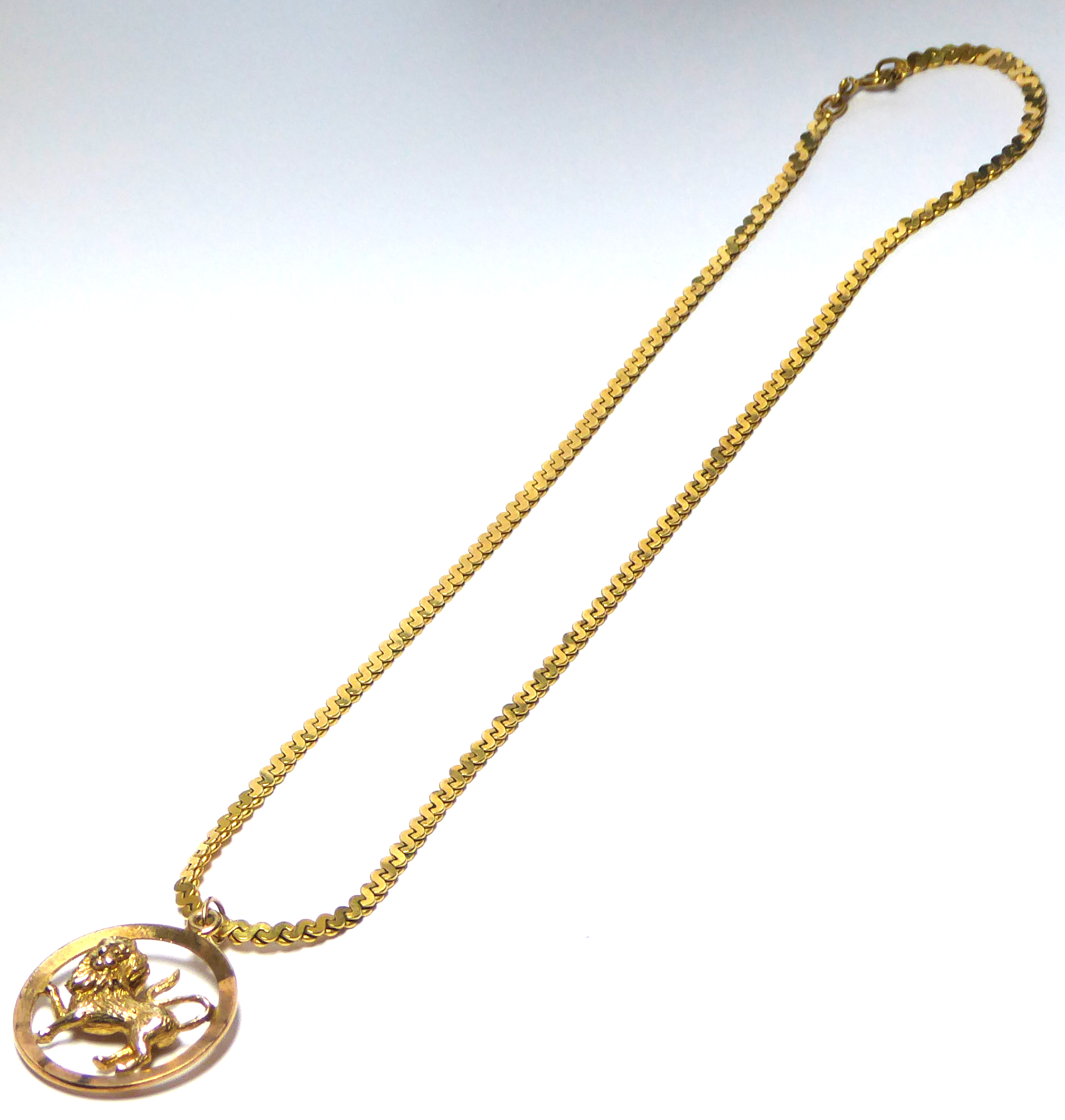 A VINTAGE 9CT GOLD PENDANT AND NECKLACE The rampant lion in pierced mount with flat scroll link