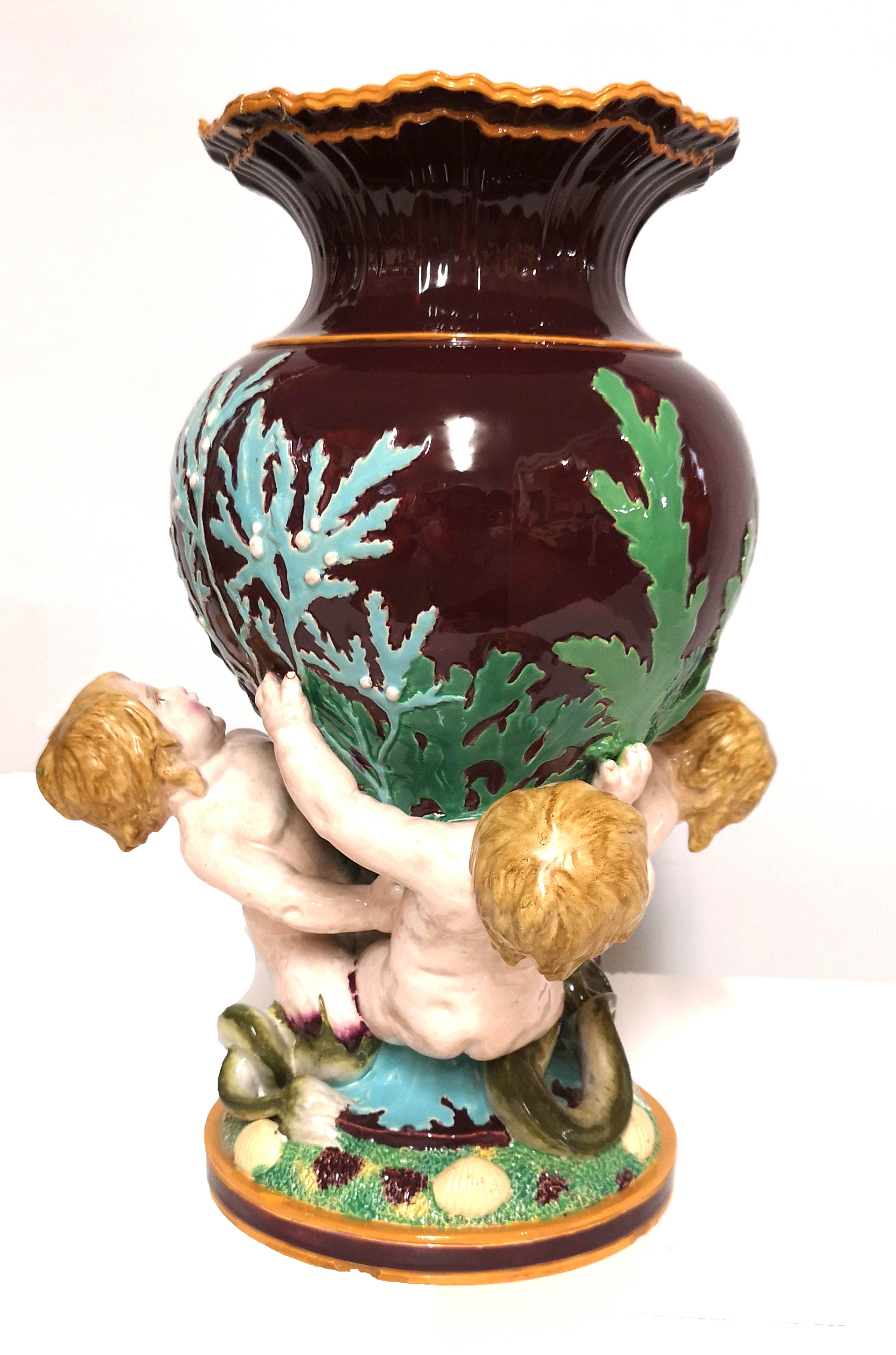 A MAJOLICA POTTERY FIGURAL JARDINIERE Having three cherub/mermaid supports with sea shells