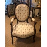 A VICTORIAN MAHOGANY SPOON BACK OPEN ARMCHAIR With carved cartouche and floral upholstery, on