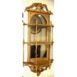 A VICTORIAN GILT FRAMED WALL MOUNTED SHELVES The basket cartouche above an arched mirrored back