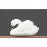 AN EARLY 20TH CENTURY JAPANESE NETSUKE IVORY CARVING OF A GLIDING SWAN, WITH INLAID EYES AND BLACK