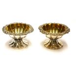A PAIR OF GEORGIAN SILVER CIRCULAR SALTS With scrolled border, gilt interior and fluted base,