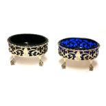 A PAIR OF GEORGIAN SILVER AND BLUE GLASS OVAL SALTS With pierced scrolled decoration raised on eagle