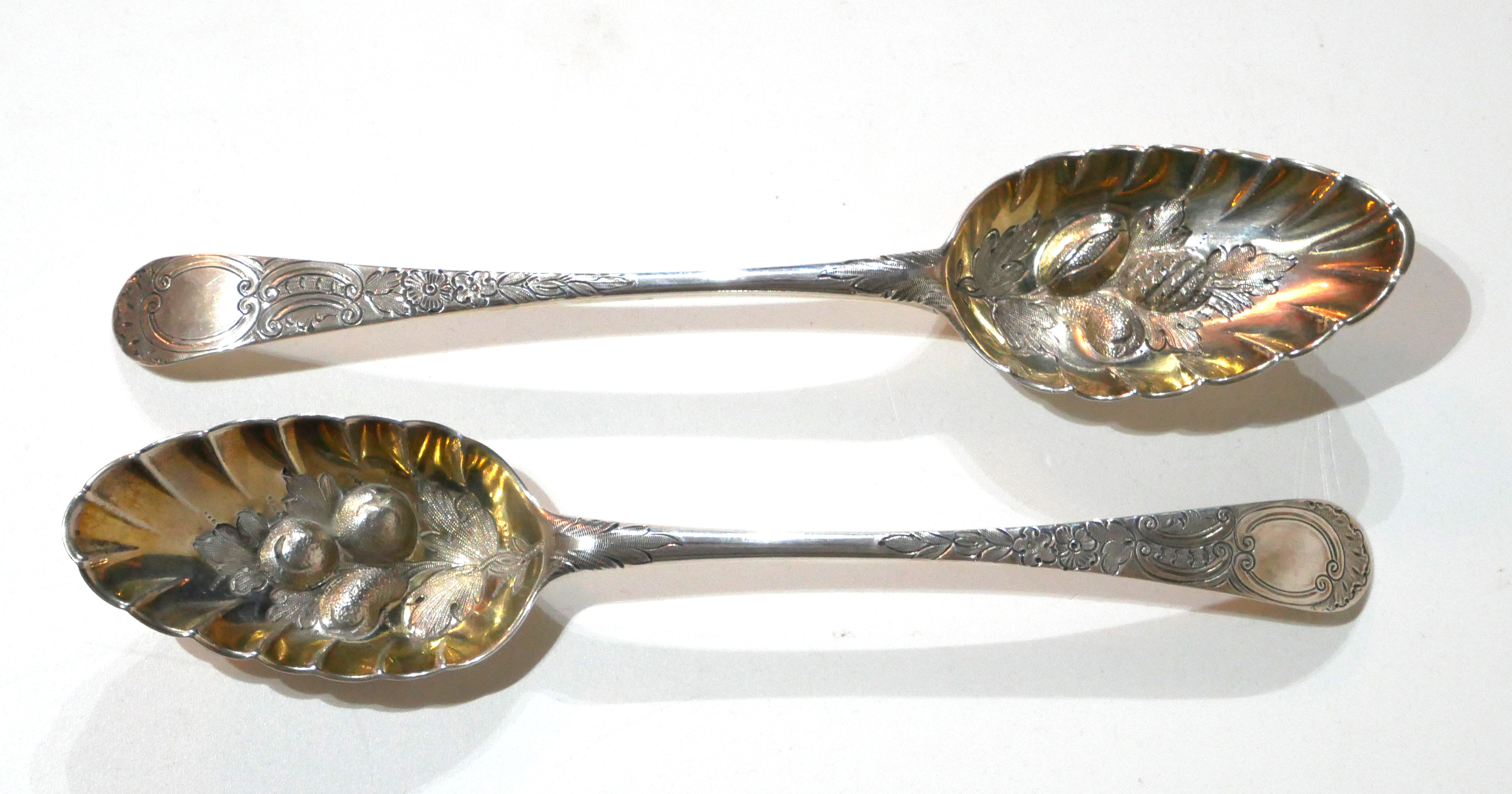 A PAIR OF GEORGIAN NEWCASTLE SILVER BERRY SPOONS Having fine engraved decoration and embossed