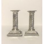 A PAIR OF VICTORIAN HALLMARKED SILVER CANDLESTICKS With candy twist columns on stepped platform