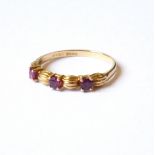 AN 18CT GOLD AND RUBY THREE STONE RING The three round cut stones set in an Art Deco form mount (