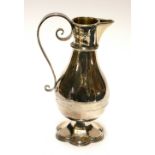 A VICTORIAN ECCLESIASTICAL SILVER BALUSTER FORM JUG With scrolled handle and fluted foot rim,