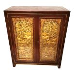 AN EARLY 20TH CENTURY CHINESE TWO DOOR SIDE CABINET With heavily carved gilded panels set behind