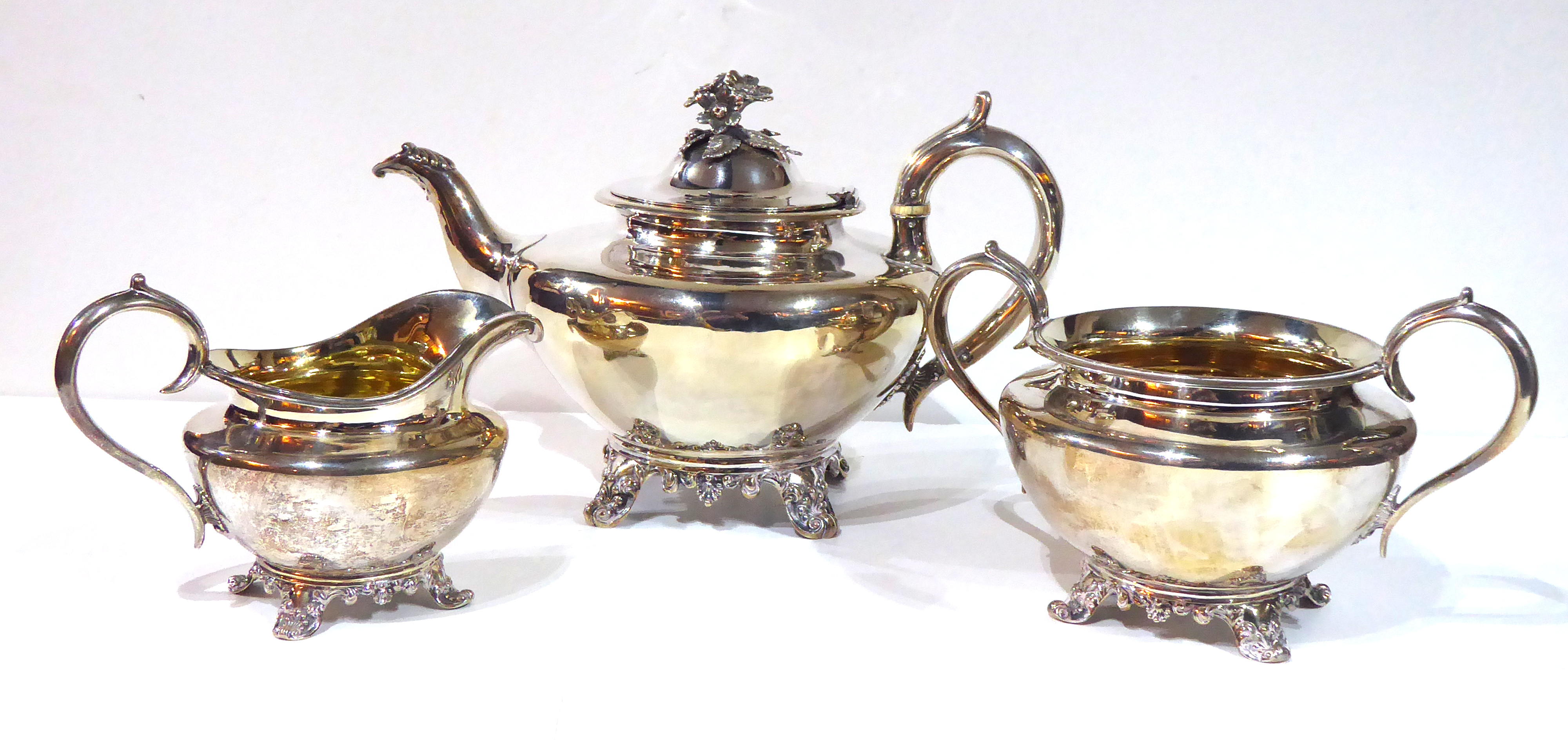 A VICTORIAN SILVER THREE PIECE TEA SERVICE Comprising a large teapot with floral finial, sugar basin