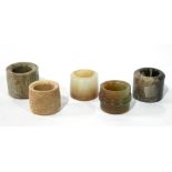 FIVE CHINESE ARCHAISTIC CYLINDRICAL JADE ARCHER'S RINGS Three carved in shallow raised relief with