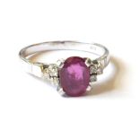 A VINTAGE 14CT WHITE GOLD AND RUBY AND DIAMOND RING Having an oval cut stone flanked by diamonds (
