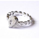 AN 18CT WHITE GOLD AND DIAMOND HALF ETERNITY RING Having a pavé set scroll with round cut diamonds