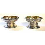 A PAIR OF GEORGIAN SILVER CIRCULAR SALTS With embossed floral decoration and flared foot rim,